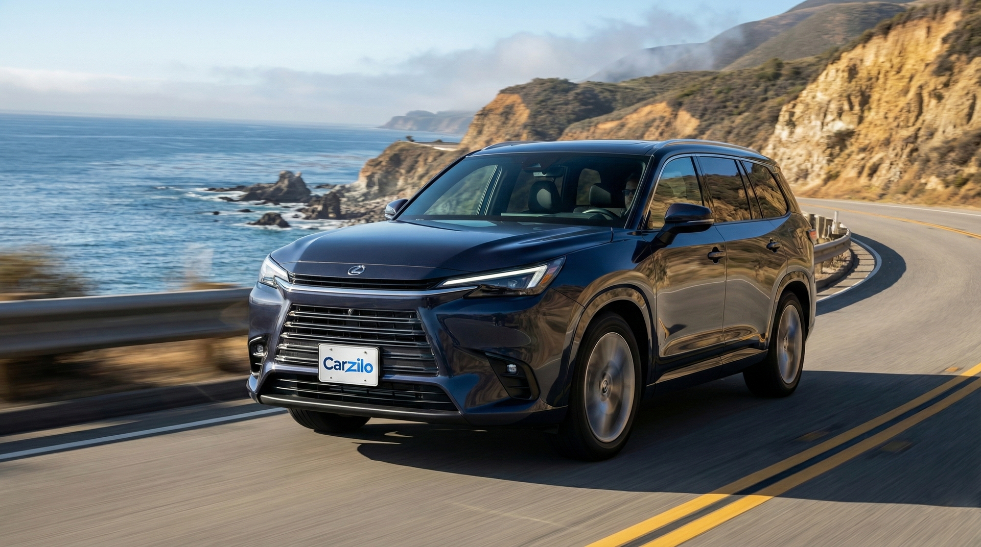 California Buyers Want Your LEXUS TX Dark blue LEXUS TX SUV driving along a winding California coastal highway, ideal for owners ready to sell their car.