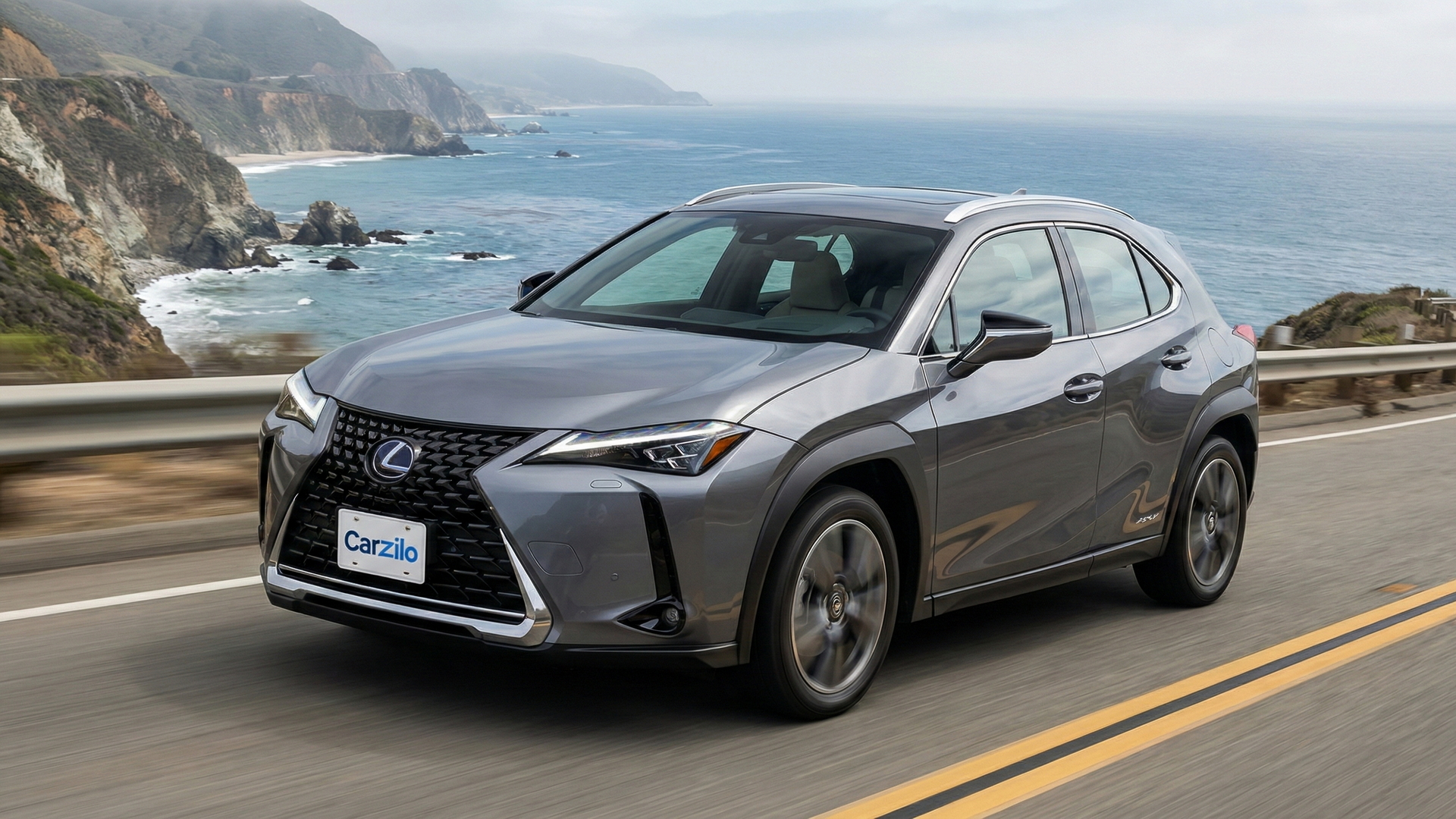 Sell Your Lexus UX in California Lexus UX gray compact SUV driving along a California coastal highway, ideal for owners looking to sell their car.