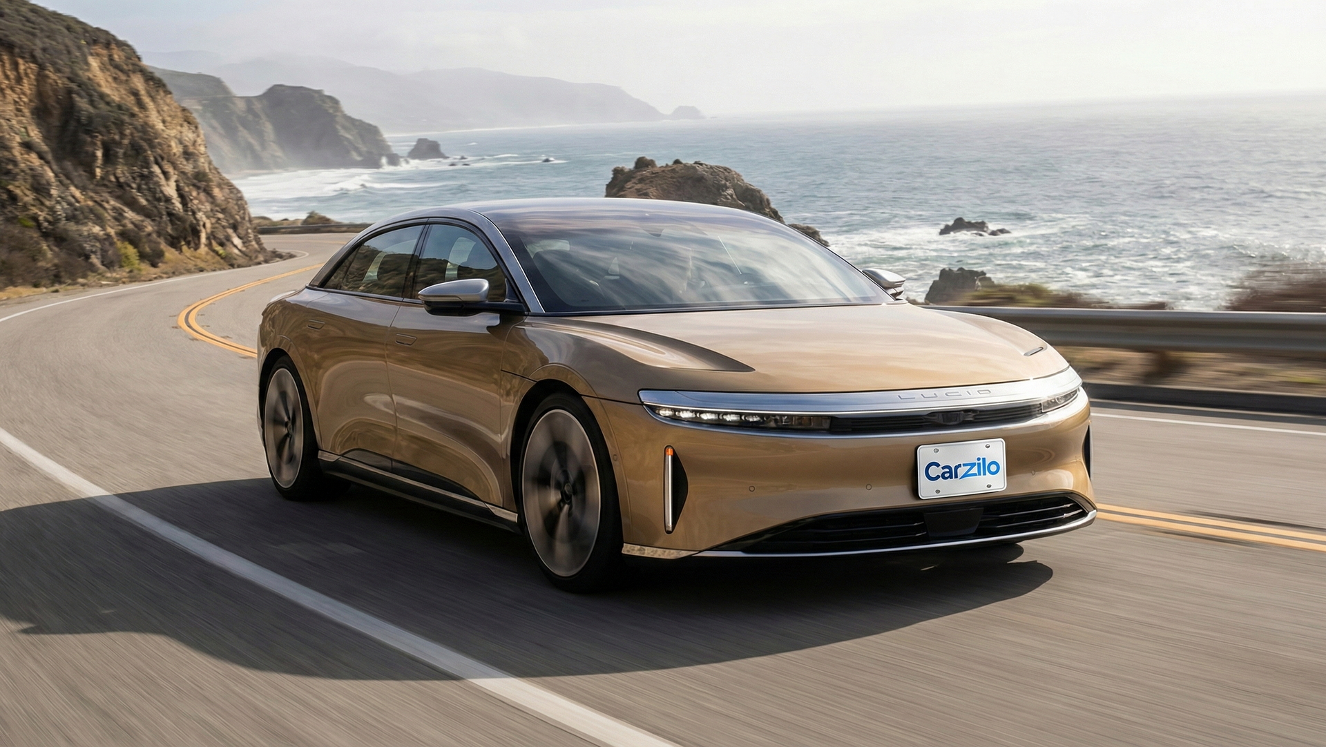 Sell Your Lucid Air Sapphire In California Lucid Air Sapphire gold electric sedan driving along a California coastal highway, ideal for owners looking to sell their car quickly.