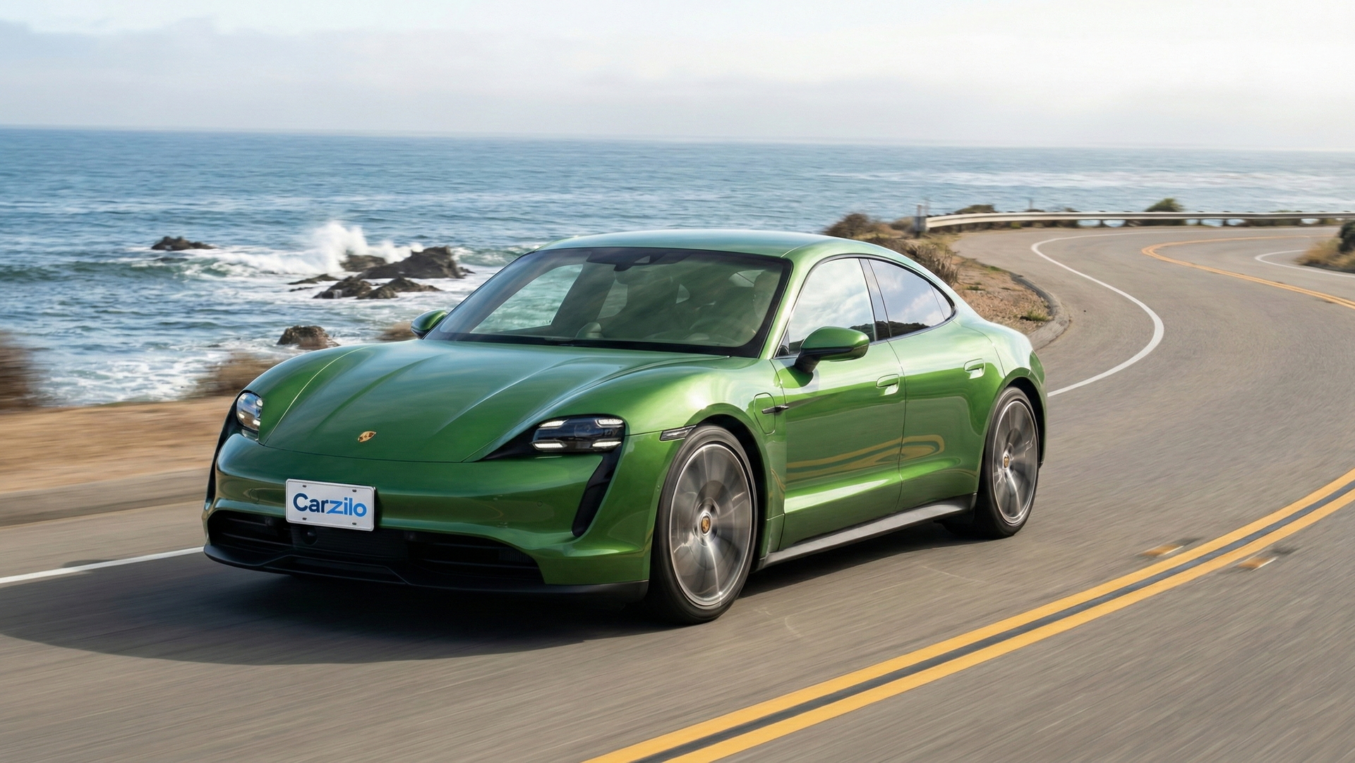 Porsche Taycan green electric sedan driving along a winding California coastal highway, ideal for drivers looking to sell their car fast.