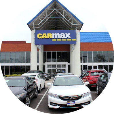 Beat My Carmax Offer Online - Carzilo Comparison A circular-cropped photo of a CarMax dealership building with parked cars in the lot, showing how Carzilo can beat my Carmax offer online.